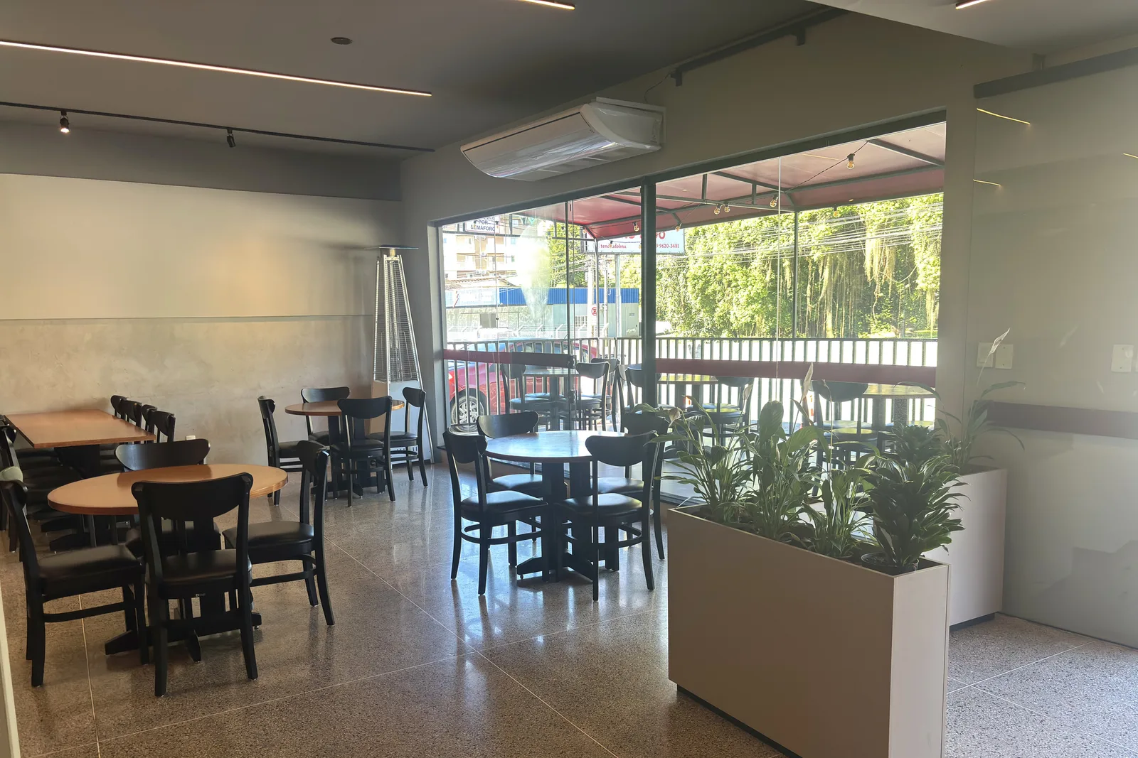 Varanda do restaurante com mesas e plantas